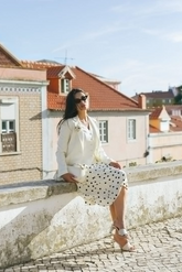 a lady in a white vest, a white blazer and a white skirt with black polka dots
